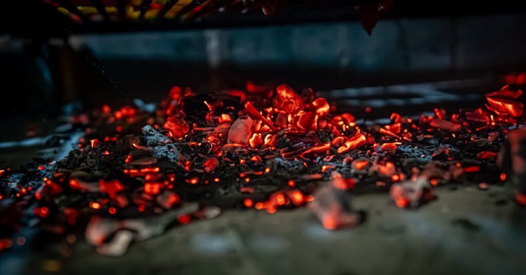 Close-up of glowing coals in a grill, highlighting the intense heat and vibrant colors.